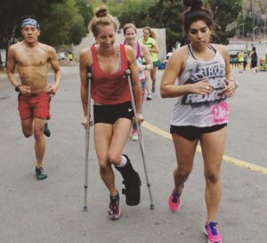 una mujer en muletas recorre un maratón al lado de una corredora, mientras atrás va otro corredor que se ve muy esforzado por alcanzarlas. Probablemente ésta mujer sea la única coja más rápida que yo
