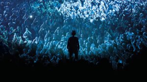 un hombre (Nick Cave) observa desde arriba del escenario a la gente, que está mágicamente iluminada con luz azul, y da la sensación de ser un hermoso océano de cabezas entusiasmadas