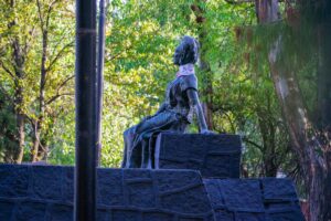 a lo alto de una estructura de piedra, la estatua de Frida Kahlo mira impertérrita a la nada, recargada sobre un brazo, detenida en el tiempo, siendo orgullosa pero también siendo metal inmóvil
