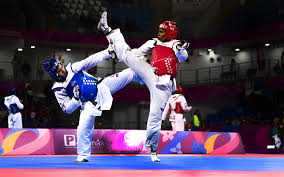 en un torneo dos practicantes de tae kwon do luchan. Uno da una tremenda patada a la espalda de su contrincante, mientras el otro manda la patada hacia el costado, haciendo gala de toda la fuerza, flexibilidad y habilidad que no tengo yo