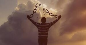 un hombre, mirando al cielo imponente, abre los brazos y rompe unas enormes cadenas